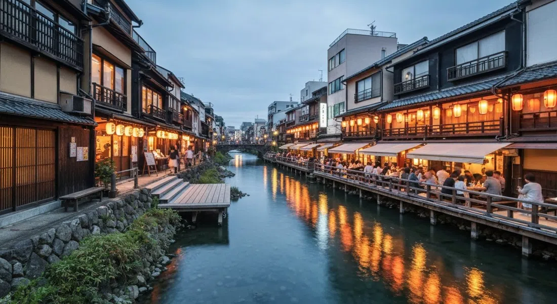 Pontocho al atardecer, faroles brillando a lo largo del estrecho callejón de machiya, plataformas de madera al lado del río extendiéndose sobre el Kamogawa para cenar en verano
