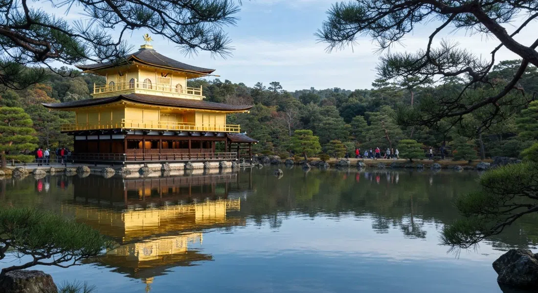 El pabellón de pan de oro de Kinkaku-ji reflejado en el estanque tranquilo a la luz de la mañana, con ramas de pino enmarcando el agua y visitantes en el camino de un solo sentido